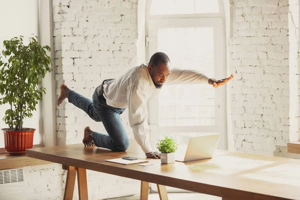 Junger afrikanisch-amerikanischer Mann macht Yoga zu Hause, während er unter Quarantäne steht und freiberuflich arbeitet — Stockfoto