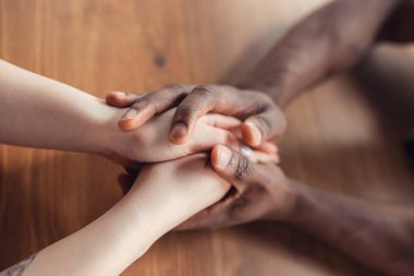 Afrika kökenli Amerikalı erkek ve beyaz kadınların el ele tutuşması.