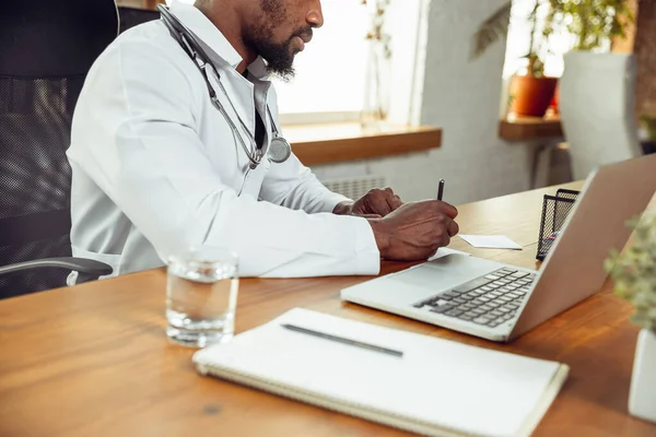 African-american doctor consulting for patient, working in cabinet, close up