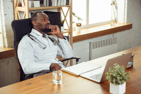 African-american doctor consulting for patient, working in cabinet, close up