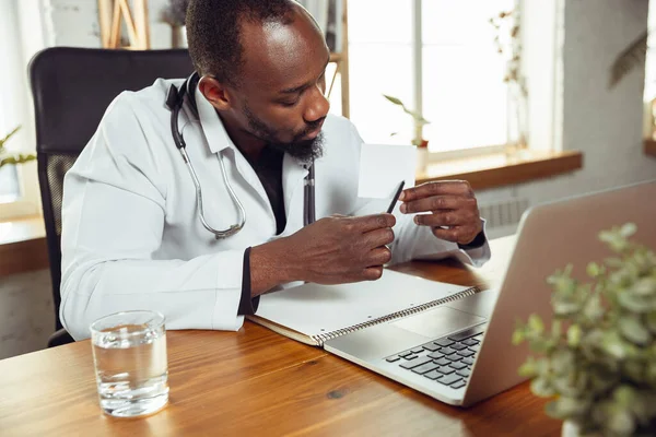 African-american doctor consulting for patient, working in cabinet, close up