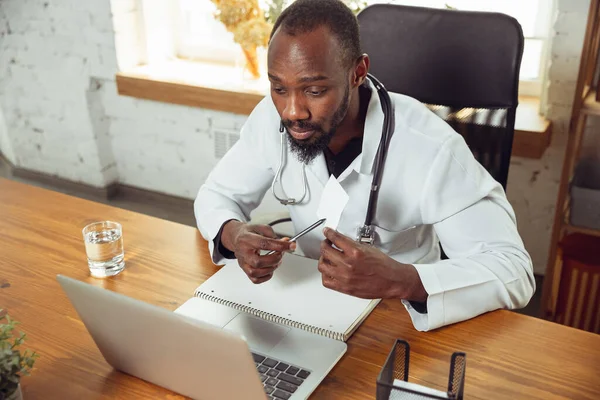 African-american doctor consulting for patient, working in cabinet, close up