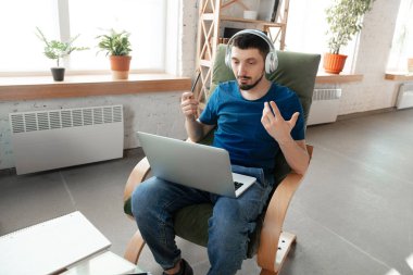 Young focused man studying at home during online courses or free information by hisself clipart