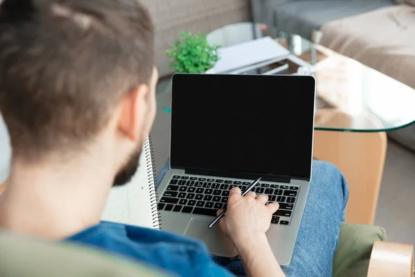 Hombre joven enfocado que estudia en casa durante cursos en línea o información gratuita por sí mismo — Foto de Stock