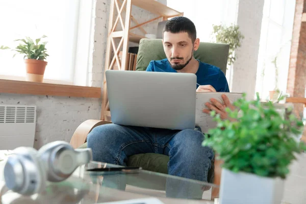 Junger fokussierter Mann lernt zu Hause während Online-Kursen oder kostenlosen Informationen selbst — Stockfoto