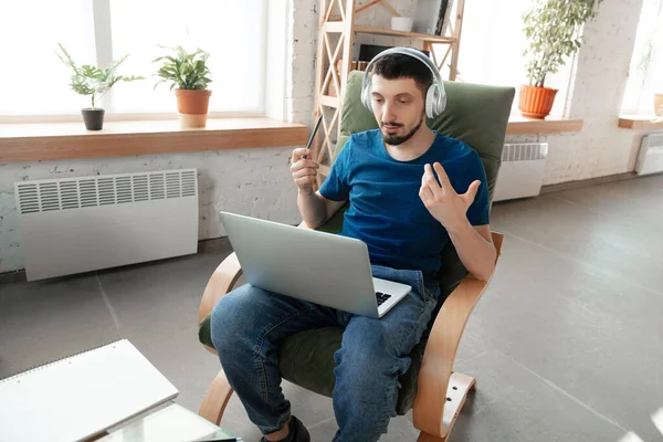 Hombre joven enfocado que estudia en casa durante cursos en línea o información gratuita por sí mismo — Foto de Stock