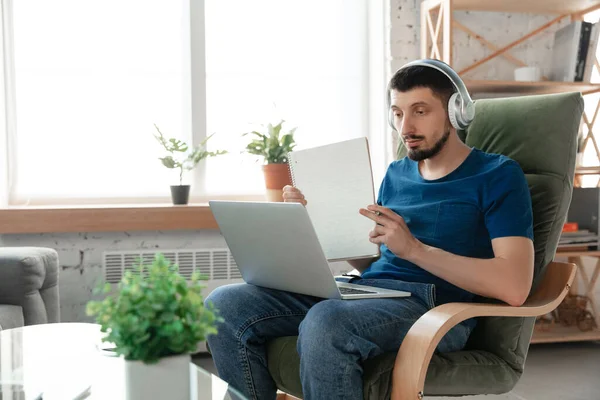 Hombre joven enfocado que estudia en casa durante cursos en línea o información gratuita por sí mismo — Foto de Stock