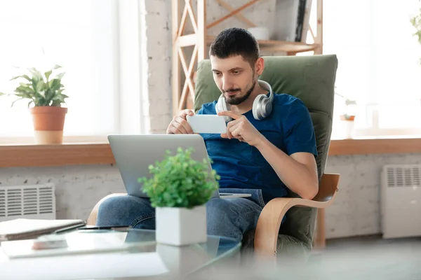 Hombre joven enfocado que estudia en casa durante cursos en línea o información gratuita por sí mismo — Foto de Stock