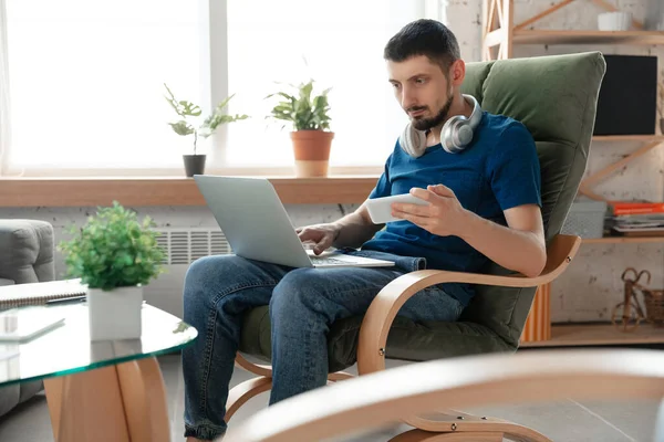 Hombre joven enfocado que estudia en casa durante cursos en línea o información gratuita por sí mismo — Foto de Stock