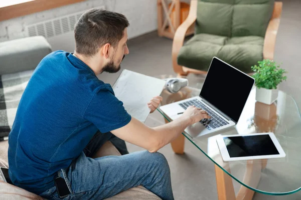 Hombre joven enfocado que estudia en casa durante cursos en línea o información gratuita por sí mismo — Foto de Stock