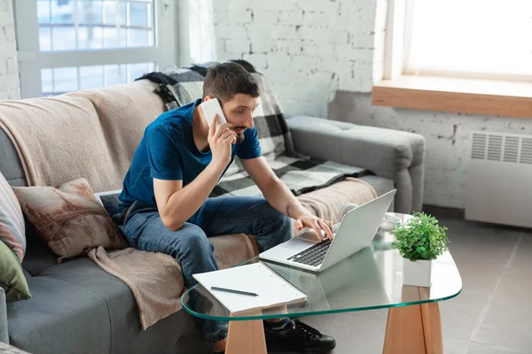 Hombre joven enfocado que estudia en casa durante cursos en línea o información gratuita por sí mismo — Foto de Stock