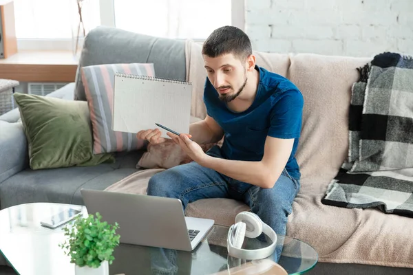 Hombre joven enfocado que estudia en casa durante cursos en línea o información gratuita por sí mismo — Foto de Stock