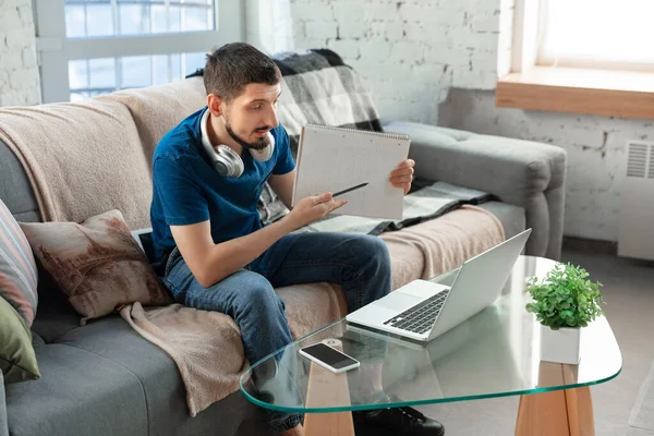 Hombre joven enfocado que estudia en casa durante cursos en línea o información gratuita por sí mismo — Foto de Stock