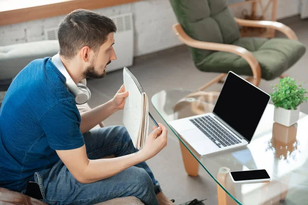 Hombre joven enfocado que estudia en casa durante cursos en línea o información gratuita por sí mismo — Foto de Stock