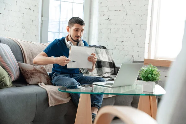 Hombre joven enfocado que estudia en casa durante cursos en línea o información gratuita por sí mismo — Foto de Stock