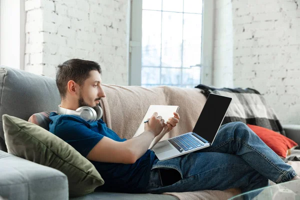 Junger fokussierter Mann lernt zu Hause während Online-Kursen oder kostenlosen Informationen selbst — Stockfoto