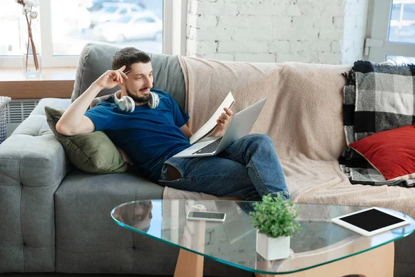 Hombre joven enfocado que estudia en casa durante cursos en línea o información gratuita por sí mismo — Foto de Stock