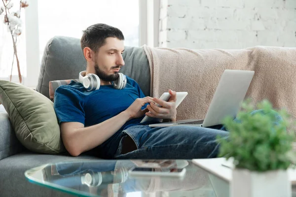 Hombre joven enfocado que estudia en casa durante cursos en línea o información gratuita por sí mismo — Foto de Stock