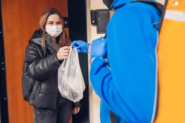 Contacless delivery service during quarantine. Man delivers food and shopping bags during isolation — Stock Photo, Image