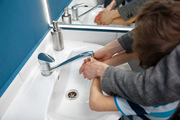 Mãe lavar as mãos de seu filho cuidadosamente no banheiro de perto. Prevenção da infecção e disseminação do vírus da pneumonia — Fotografia de Stock