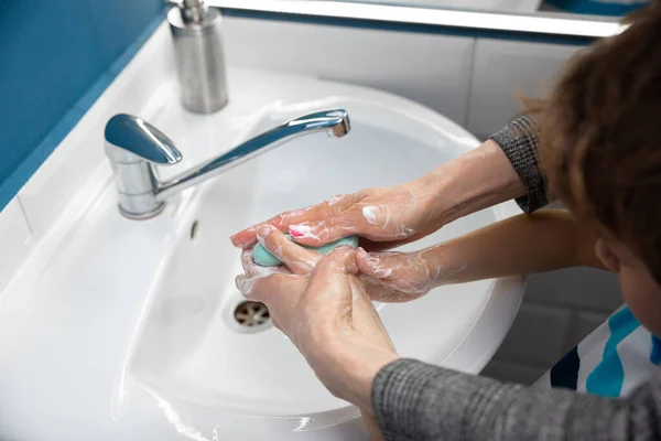 Moeder wassen handen haar zoon zorgvuldig in de badkamer close-up. Preventie van infectie en verspreiding van longontsteking — Stockfoto
