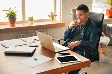 Yaratıcı iş yeri. İlham için istediğiniz gibi düzenli çalışma alanı. Makamında rahat bir şekilde çalışan bir adam.