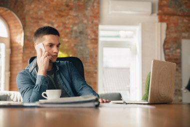Yaratıcı iş yeri. İlham için istediğiniz gibi düzenli çalışma alanı. Makamında rahat bir şekilde çalışan bir adam.