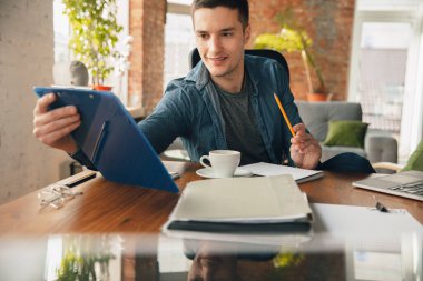 Yaratıcı iş yeri. İlham için istediğiniz gibi düzenli çalışma alanı. Ofiste kahveyle çalışan adam.