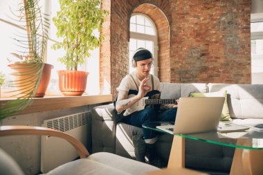 Çevrimiçi kurslar sırasında evde okuyan genç bir adam ya da kendi başına ücretsiz bilgi edinen biri.