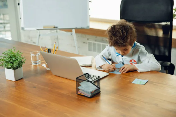 Маленький кавказький хлопчик як лікар консультує пацієнта, працює в кабінеті, крупним планом — стокове фото