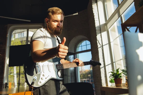 Vit musiker som spelar gitarr under online konsert hemma isolerad och i karantän, tummen upp, trevlig — Stockfoto