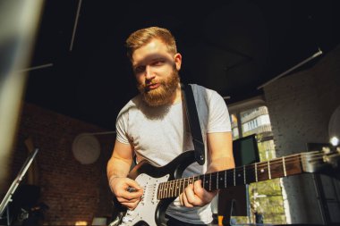 Kafkasyalı müzisyen evdeki online konser sırasında gitar çalıyor izole edilmiş ve karantinaya alınmış, gün ışığında etkileyici bir doğaçlama.