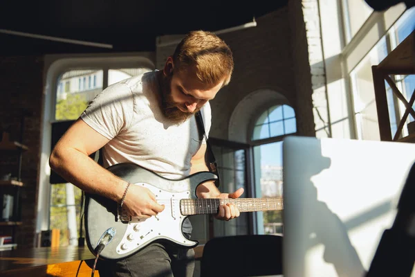 Kaukasischer Musiker spielt Gitarre bei Online-Konzert zu Hause isoliert und unter Quarantäne, improvisiert eindrucksvoll im Sonnenlicht — Stockfoto