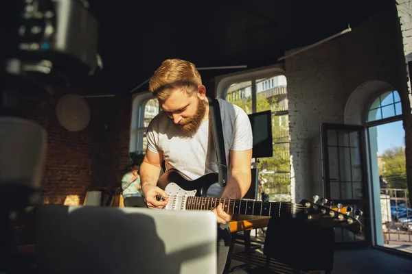 Musicista caucasico suonare la chitarra durante il concerto online a casa isolata e in quarantena, impressionante improvvisazione alla luce del sole — Foto Stock