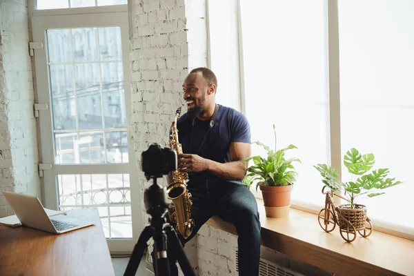 Afroamerikanischer Musiker spielt Saxofon bei Online-Konzert zu Hause isoliert und unter Quarantäne und lacht — Stockfoto