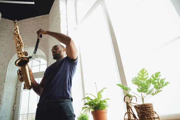 Músico afroamericano tocando saxofón durante concierto en línea en casa aislado y en cuarentena, atento, enfocado — Foto de Stock