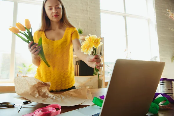 Флорист на работе: женщина показывает, как сделать букет с тюльпанами, работает на дому концепции, выбирая цветы — стоковое фото