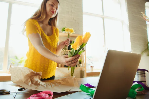 Florista en el trabajo: mujer muestra cómo hacer ramo con tulipanes, trabajando en el concepto de casa, la elección de flores — Foto de Stock