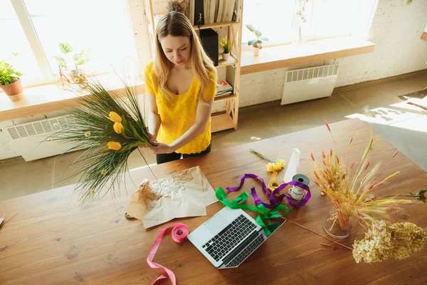 Florista en el trabajo: mujer muestra cómo hacer ramo con tulipanes, trabajando en el concepto de casa, la elección de flores — Foto de Stock