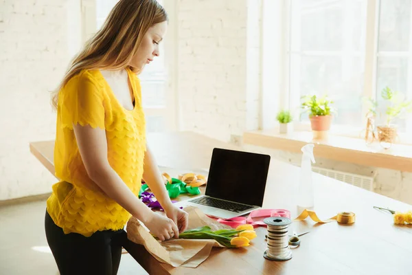 Fleuriste au travail : la femme montre comment faire un bouquet avec des tulipes, travailler à la maison concept, préparer des fleurs — Photo