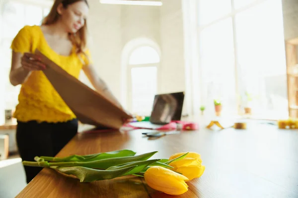 Fleuriste au travail : une femme montre comment faire un bouquet avec des tulipes, travailler à la maison concept, en utilisant du papier couverture — Photo