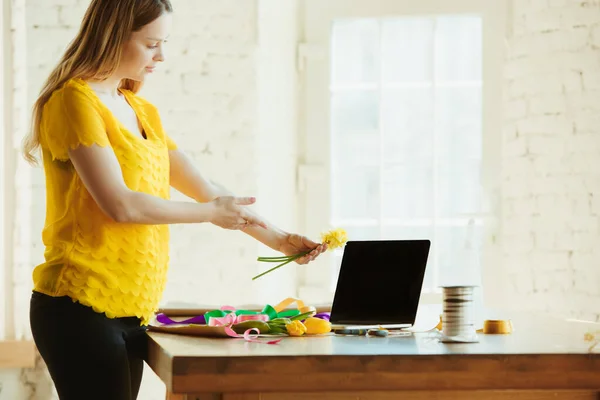 Florista en el trabajo: mujer muestra cómo hacer ramo con tulipanes, trabajando en el concepto de casa, añade narcisos — Foto de Stock