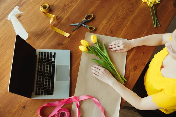 Флорист на работе: женщина показывает, как сделать букет с тюльпанами, работая на дому концепции, вид сверху — стоковое фото