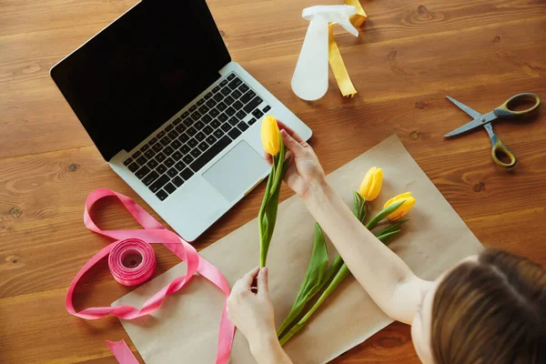 Florista en el trabajo: mujer muestra cómo hacer ramo con tulipanes, trabajando en el concepto de casa, vista superior — Foto de Stock