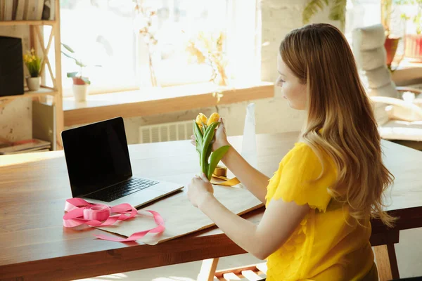 Floristería en el trabajo: mujer muestra cómo hacer ramo con tulipanes, trabajando en el concepto de casa, decoración — Foto de Stock