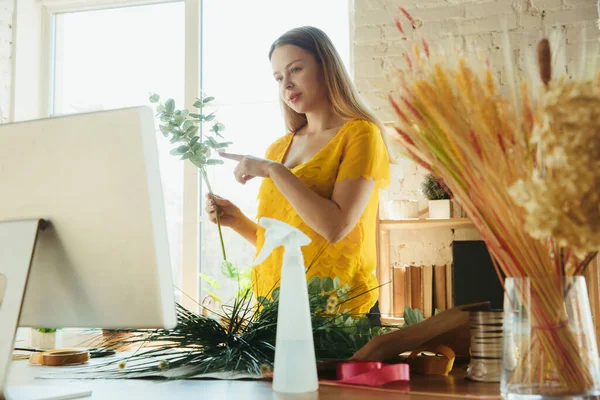 Fleuriste au travail : la femme montre comment faire un bouquet, travailler à la maison concept, choisir des plantes pour la composition — Photo