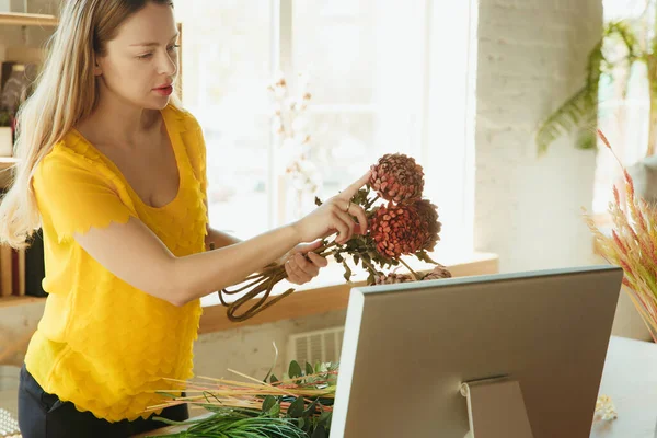 Флорист за работой: женщина показывает, как сделать букет, работая на дому концепции, выбирая растения для композиции — стоковое фото