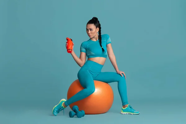 Vacker ung kvinnlig idrottare tränar på blå studio bakgrund, monokrom porträtt — Stockfoto
