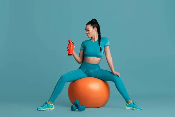 Vacker ung kvinnlig idrottare tränar på blå studio bakgrund, monokrom porträtt — Stockfoto