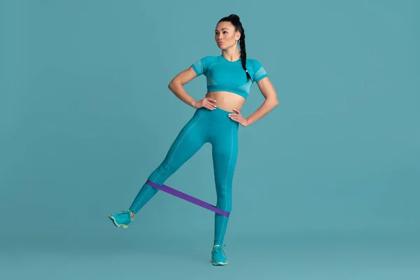 Krásná mladá žena sportovec cvičení na modrém pozadí studia, monochromatický portrét — Stock fotografie